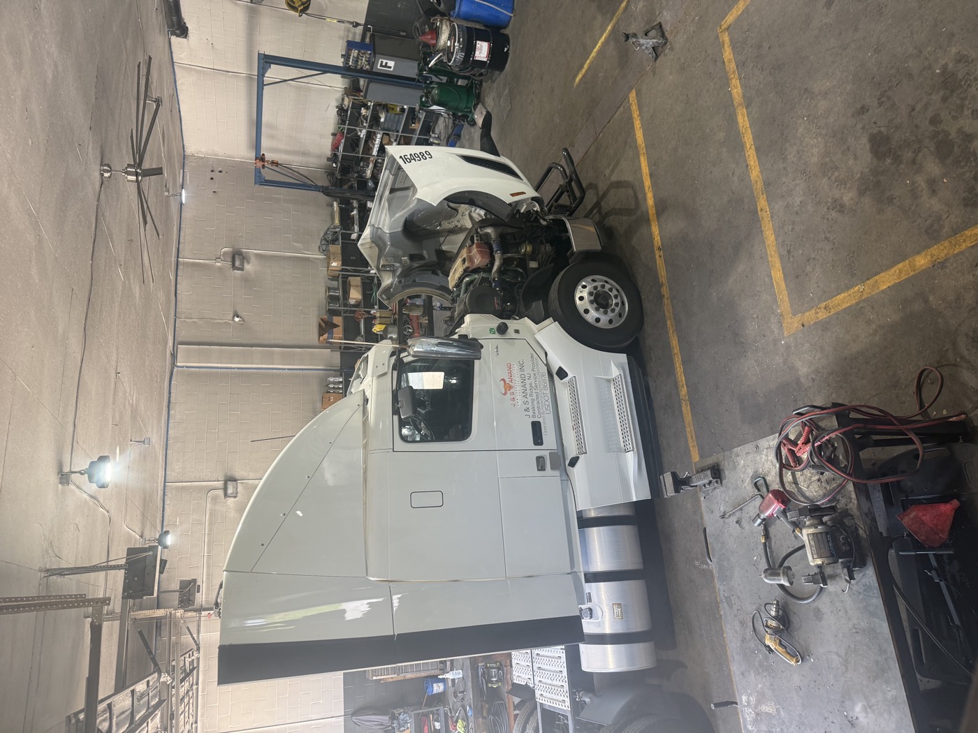 J&S Anand tractor with the hood tilted open inside the shop