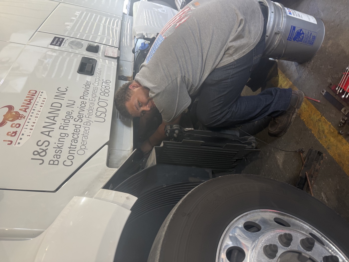 J&S Anand mechanic Donovan working behind the front wheel of a Volvo tractor
